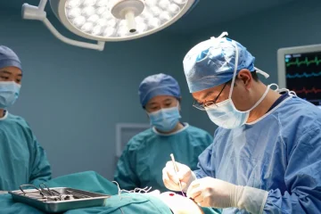 Surgeon performing sutures during surgery, showcasing precision and medical instruments in a bright operating room